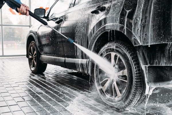 Woman washing his car in a self service car wash station.Car wash self service.