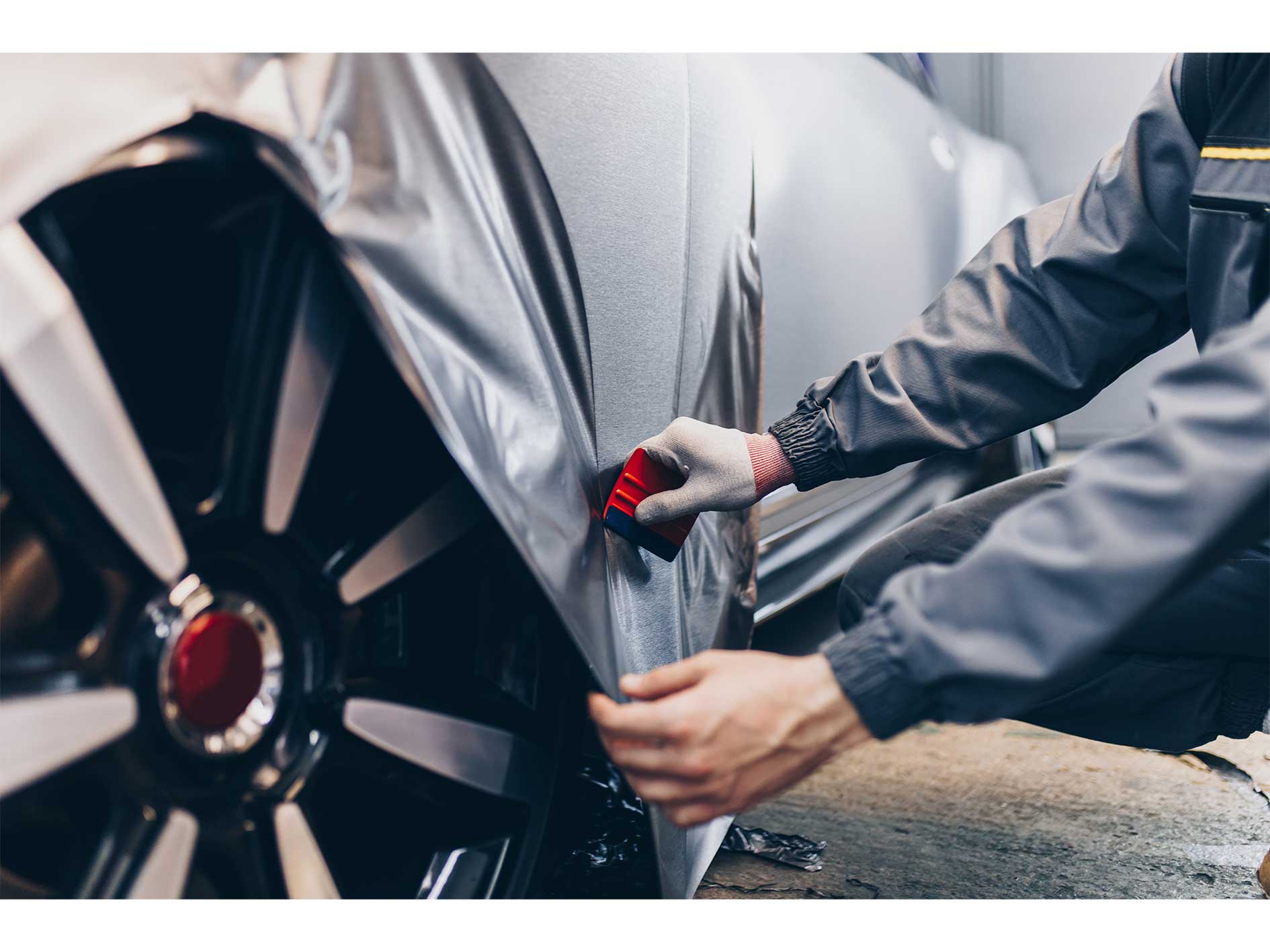 Car wrapping specialist putting vinyl foil or film on car. Selective focus