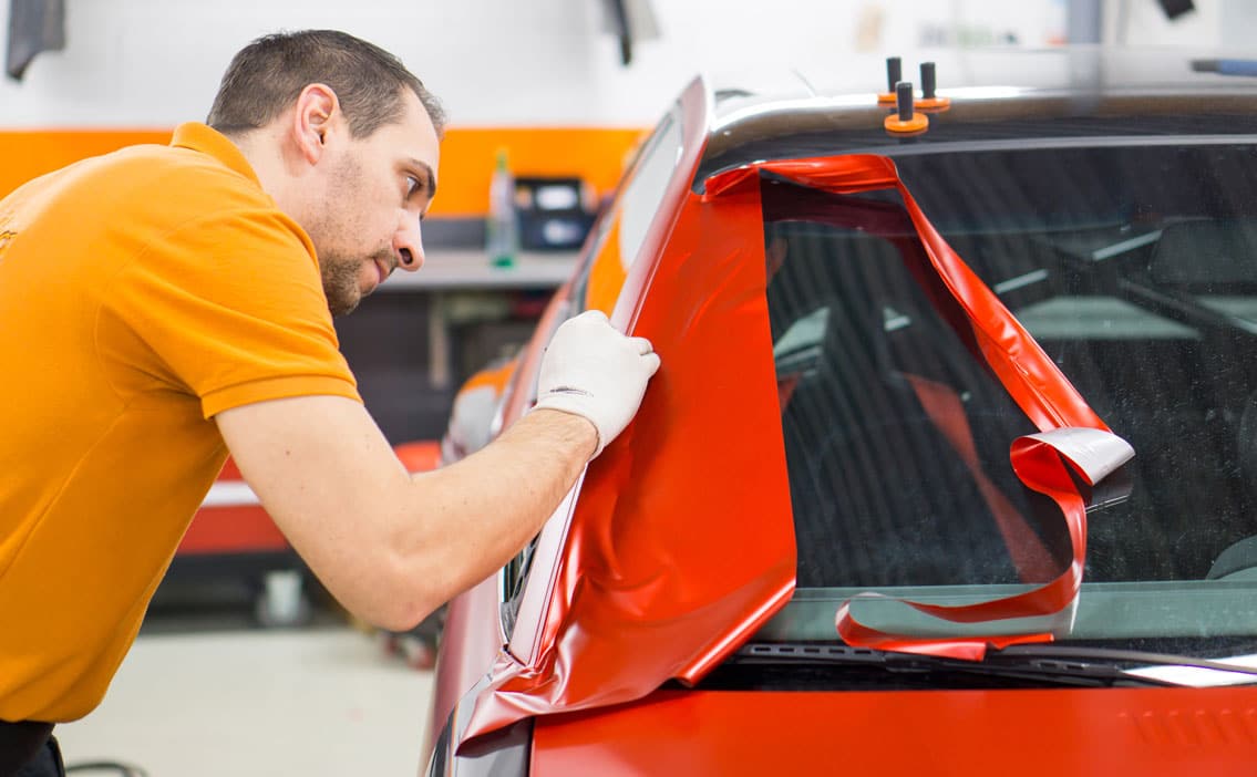 Mitarbeiter betreibt car wrapping an einem Fahrzeug